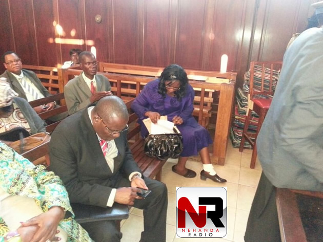 Dorothy Mabika retrieves her papers from her purse for submission while Manicaland Governor Chris Mushowe plays with his phone.