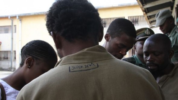 George Renene Longange, 41, shows the back of his prison clothing with the words, "Super Devil" inscribed, as he talks to the media at Harare Remand Prison, in Harare, Zimbabwe. (AP)