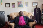 Anglicans battle to clear Kunonga’s debt Bishop from Hell: Nolbert Kunonga in his Harare offices with a picture of Robert Mugabe in the background