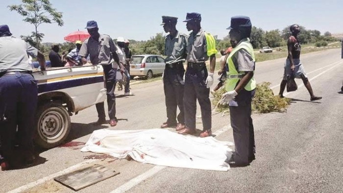 Police details prepare to remove the body of Peter Gusha Mufandirwa from the accident scene in Masvingo (The Chronicle)