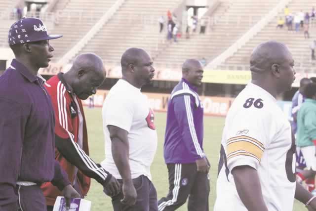 HARD HAT AREA . . . In unprecedented move, under-fire Dynamos head coach David “Yogi” Mandigora (second from left) leaves the pitch at the National Sports Stadium surrounded by “bouncers” or bodyguards at the end of yesterday’s Premiership match against Triangle which ended in a 1-1 draw. — (Picture by Tawanda Mudimu)