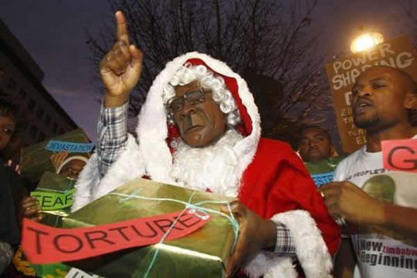 A protester dressed as Father Christmas and wearing a Robert Mugabe mask holds Christmas gifts