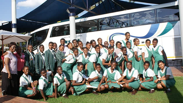 Girls High School students pose for a picture with their luxury bus in the background