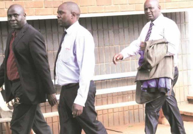 CMED boss Davison Mhaka (left) walks out of the Harare Magistrates’ Court after paying his $500 bail. He is accompanied by two friends who unsuccessfully tried to conceal his blue jacket to avoid photographers. (Picture by John Manzongo)