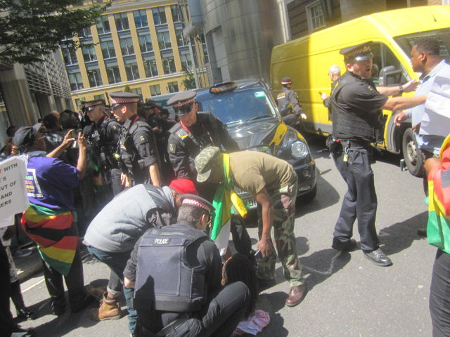 Zimbabwean demonstrators lay down in the road outside the conference in London addressed by Zimbabwe’s Finance Minister Patrick Chinamasa preventing him from leaving for more than an hour.