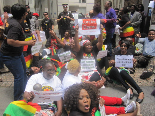 Zimbabwean demonstrators lay down in the road outside the conference in London addressed by Zimbabwe’s Finance Minister Patrick Chinamasa preventing him from leaving for more than an hour.
