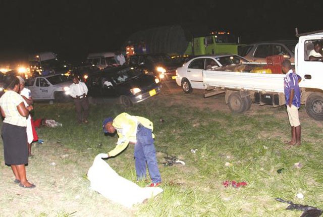 A policeman covers the body of one of the five people killed after a Chitungwiza-bound commuter omnibus burst a tyre and overturned near Koala Park Abattoir last night. — (Picture by John Manzongo)