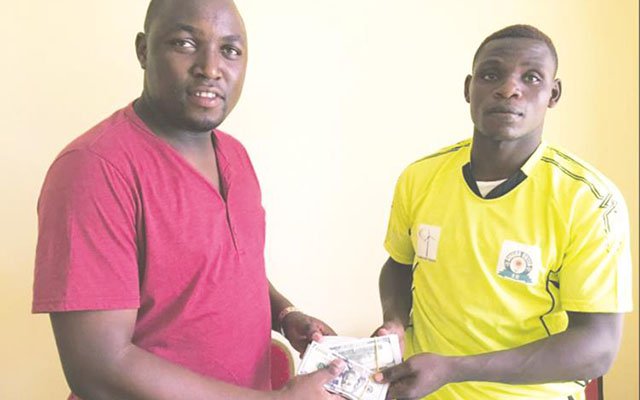ALL ABOUT THE BENJAMINS . . . Zimbabwe international defender Elisha Muroiwa (right) is shown being handed the bills of cash by his agent in Tanzania