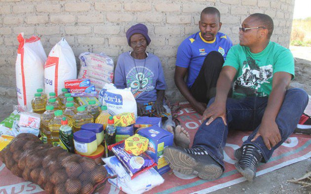 Mbuya Dembo after receiving groceries from Gerald Mhondiwa (right) and Terrence Kandima