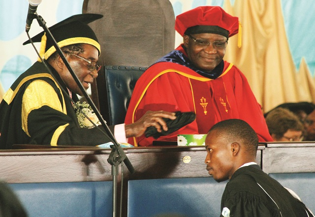 President Mugabe caps Forget Mutema who graduated with First Class Bachelor of Accountancy Honours Degree at the Bindura University of Science Education’s 16th graduation ceremony in Bindura yesterday, looking on is Higher and Tertiary Education minister Professor Jonathan Moyo. —(Picture by Tawanda Mudimu)