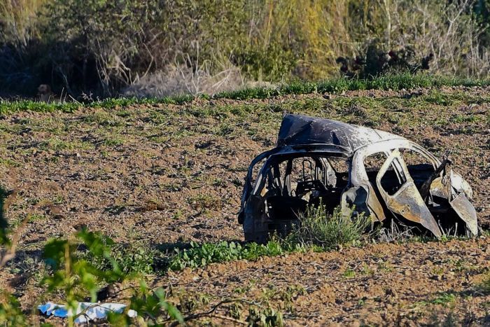 The wreckage of the car of investigative journalist Daphne Caruana Galizia lies next to a road