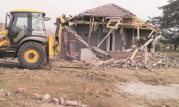 A Harare City Council front-end loader destroys an illegal brick-under-tile house belonging to a Morning Glory Housing Cooperative member in Warren Park D in 2015