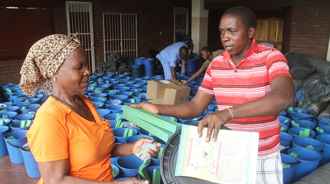 Mrs Olivia Nyuke (left) from Glen View 8 receives water containers, bars of washing soap and water treating tablets from Mr Collin Bacha at Glen View 1 Hall in Harare yesterday. The non-food items were donated by Unicef to residents in cholera-affected suburbs and distributed by Oxfam. — Picture by Kudakwashe Hunda