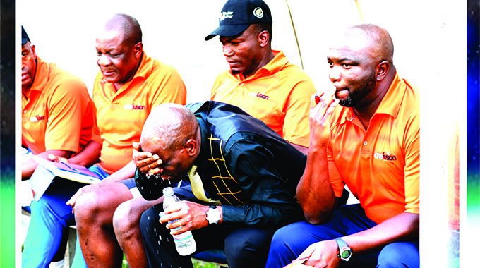 IT’S ALL GLOOMY . . . Dynamos coach Lloyd Mutasa (second from right) turns to bottled water to wash away his blues as his team huffed and puffed against Harare City at Rufaro.