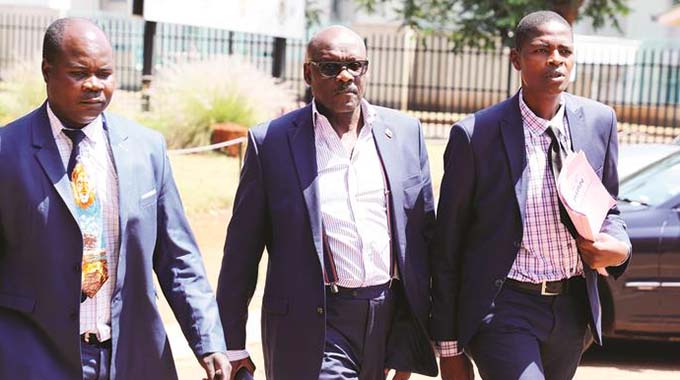 Former Health and Child Care Minister David Parirenyatwa (centre) arrives at the Harare Magistrates’ Courts in the company of detectives yesterday