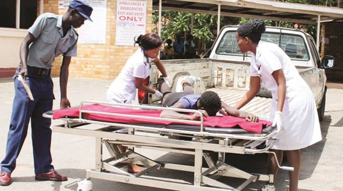Gwanda Provincial Hospital nurses lift one of the men who was assaulted for selling fake gold onto a stretcher from a police van