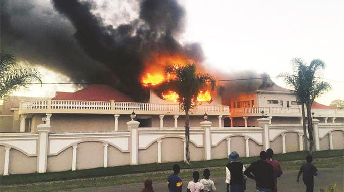 PASSERS-BY watch as fire guts a wing of Prophet Magaya’a Yadah Hotel in Waterfalls