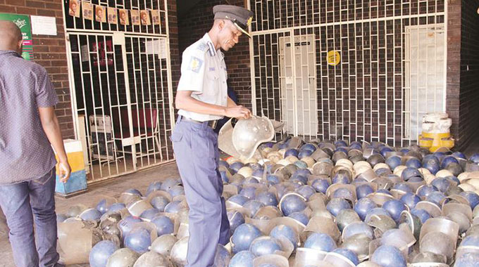 Zimbabwe Republic Police Assistant Commissioner Joshua Kadungu (Crime and Operations Harare) looks at helmets that were recovered in Harare yesterday. — Picture: Shepard Ngwaru