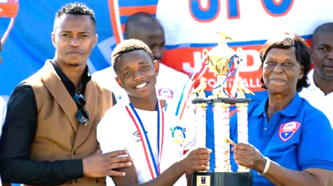 FROM BEIJING WITH LOVE . . . Anatoria Musanhu (right), mother of China-based former Zimbabwe youth international footballer Walter Musanhu (left), hands over the winners trophy to young Roy Dzomba of CUMA from Kadoma after they won the Jadel Under-15 tournament which was held at Belgravia Sports Club on Saturday as part of the launch of Walter Musanhu’s Jadel Football Academy in Harare