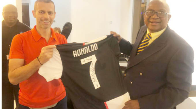 Uefa president Aleksender Ceferin hands over a jersey signed by Cristiano Ronaldo to Cosafa president Philip Chiyangwa at the Victoria Falls International Airport soon after his arrival on Friday.