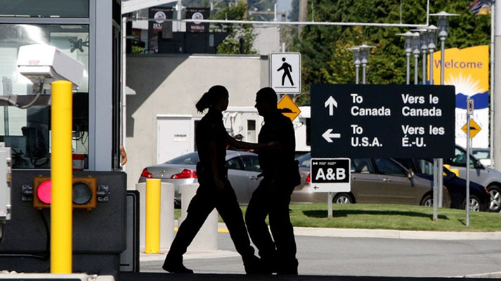 Canadian border guards are silhouetted as they replace each other at an inspection booth at the Douglas border crossing on the Canada-USA border in Surrey, B.C., on August 20, 2009. (Darryl Dyck / THE CANADIAN PRESS)