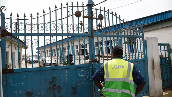 Worshippers clustered at the gate of Makoko's Celestial Church of Christ only to find policemen handing out fliers on the dangers of the virus (Picture by AFP)