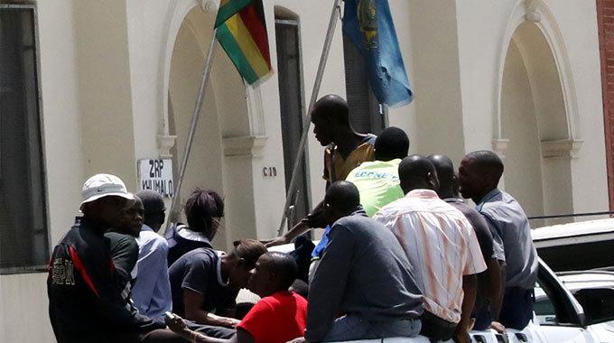 Police arrive with some of the foreign currency ‘dealers’ at Central Police Station, while picture right shows some of the caged suspects