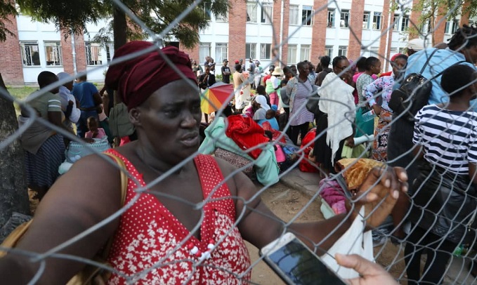 Returnees wait to receive clothing from officials at a quarantine center