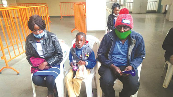 GONE BUT NOT FORGOTTEN . . . Antonneta (left), who lost both her siblings Spencer Gwasira and Galileo Muchemwa in the road accident involving Dynamos fans on their way to a league match in Gweru in 2016, sits with her husband Collen and one of Spencer’s orphans during yesterday’s presentation of the food hampers at the National Sports Stadium.