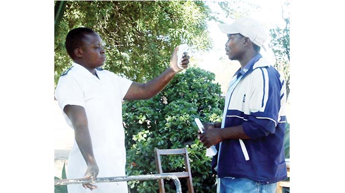 A nurse checks a patient’s temperature