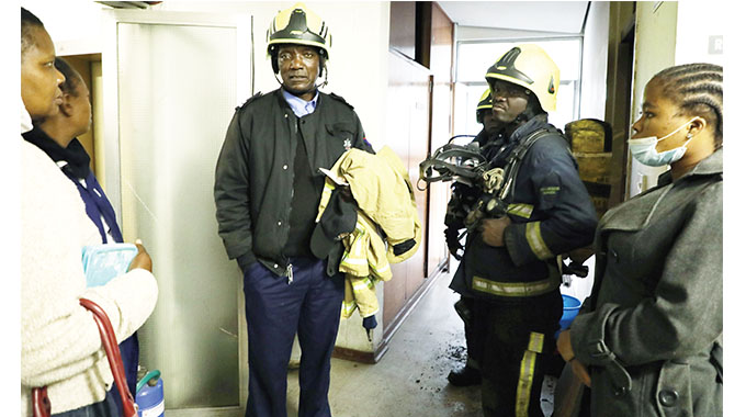 Fire Brigade officers speak to Lupane State University workers after a fire incident in one of their rooms at the National Railways of Zimbabwe owned Parkade Centre building along Fife Street, Bulawayo, yesterday. (Pic By Dennis Mudzamiri)