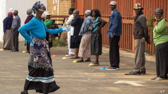 File photo: A worker wearing a face mask and gloves to protect herself against coronavirus, joins the queue to receive her social grant outside a pay point in Thokoza, east of Johannesburg