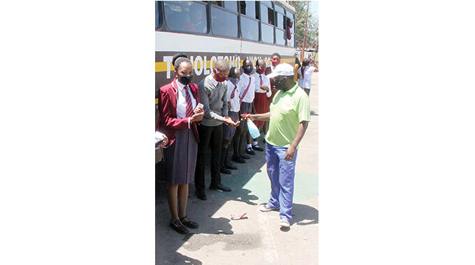Puplis are sanitised before boarding a bus back to school yesterday