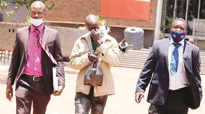 Detectives escort Gift Chemhuru as he appears at the Harare Magistrates Courts yesterday in connection with the kidnapping of a 4-week-old baby at Spar Montague recently. — Picture: Lee Maidza