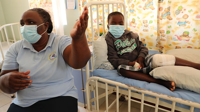 Buhera landmine explosion survivor, Listen Mufowo (on her Victoria Chitepo Provincial Hospital bed) listens attentively as her grandmother, Gogo Maria Rwavazhinji Mufowo narrates the horrific events that left her left knee almost shattered. Listen still has vivid memories of the sad event which resulted in the death of two boys.