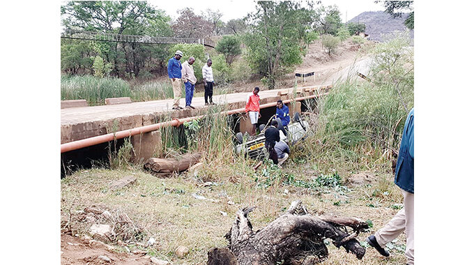 People attend to a vehicle that fell off Mtshabezi Bridge which runs over Mtshabezi River in Gwanda in this file photo