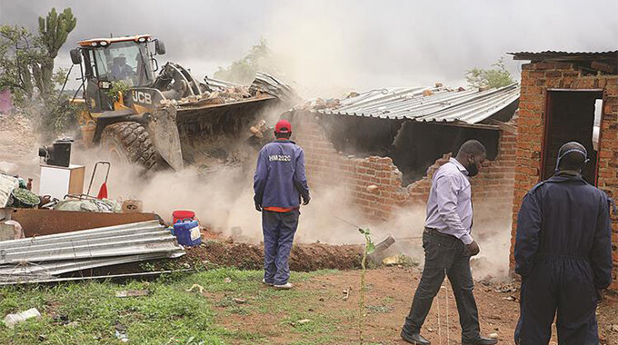 City of Harare officials demolish illegal houses in Budiriro yesterday. — Picture: Justine Mutenda