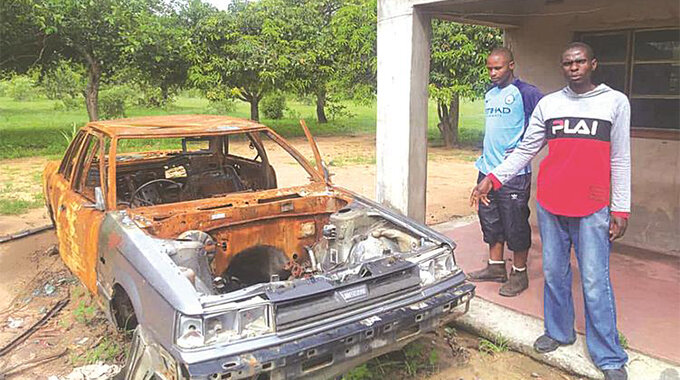 Henry Mapxashike(in red jacket) and his cousin Brine Chitiga show the vehicle that was torched by Clever at his father’s homestead in Matova Village under Chief Zimuto