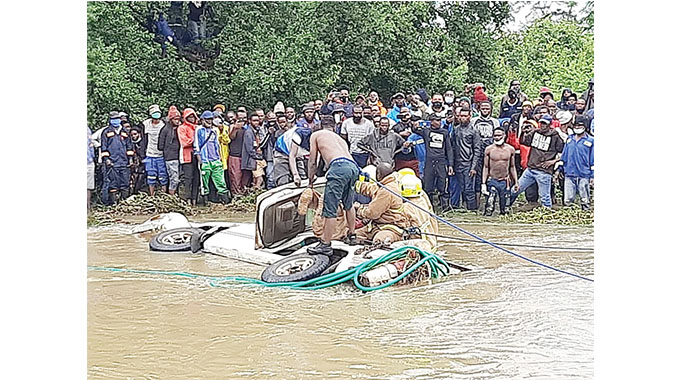 A rescue team searches for bodies in the car that was swept away by the flooded Gweru River yesterday.