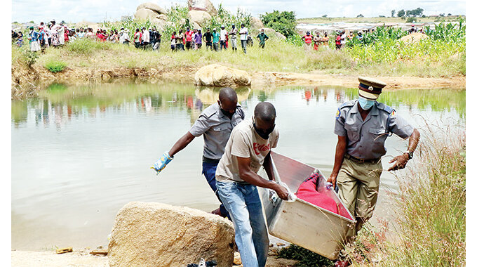 ZRP and a family member retrieve the body of a boy who drowned at a water-filled pit in Pelandaba West suburb, Bulawayo yesterday