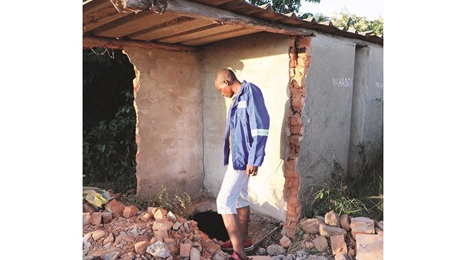 An unidentified man peeps into a disused toilet yesterday where two bodies of Mbaza Primary School Grade One pupils were dumped, in Sambaza Village, Nyanga, last Tuesday. — Picture: Tinai Nyadzayo