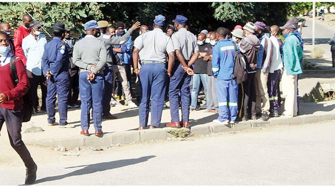 Police officers explain to the drivers and owners of impounded vehicles the protocol to get their vehicles released outside the Ross Camp gate in Bulawayo on Monday