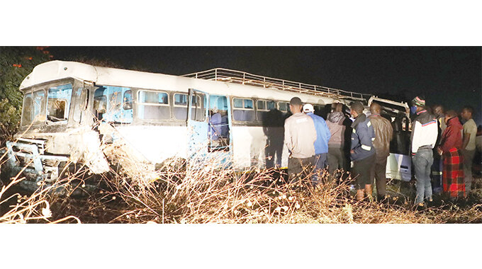 Bystanders look at the bus that was involved in an accident with a Toyota Dyna truck that killed the truck driver at the intersection of Luveve Road and Huggins Road near Josiah Chinamano Primary School in Emakhandeni suburb on Tuesday night