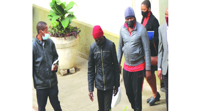 Two armed robbers Mthokozisi Moyo (second from left) and Makhosi Nkomo being escorted by police details to prison cells at the magistrates’ court housed at Tredgold Building in Bulawayo yesterday