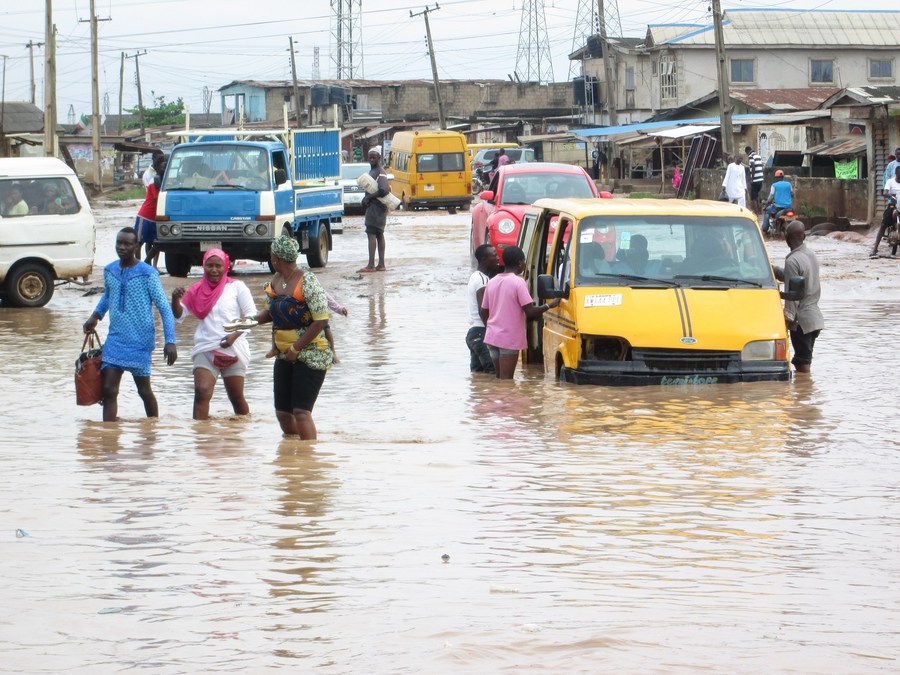 File photo shows Nigerian residents and vehicles wade through flood water after a rainstorm in Abeokuta, Ogun State, southwest Nigeria, Nov. 5, 2014. (Xinhua/Ezekiel Taiwo)