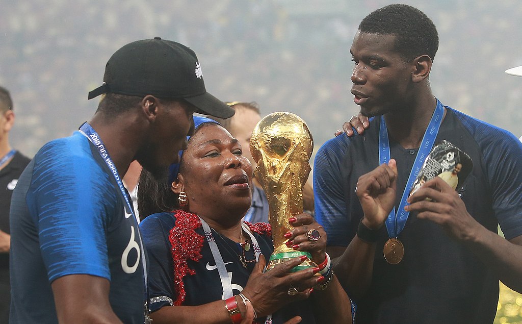 French footballer Paul Pogba and family holding the FIFA World Cup Trophy after the tournament's final match on 15 July 2018. (Picture via Антон Зайцев, CC BY-SA 3.0 GFDL, via Wikimedia Commons)